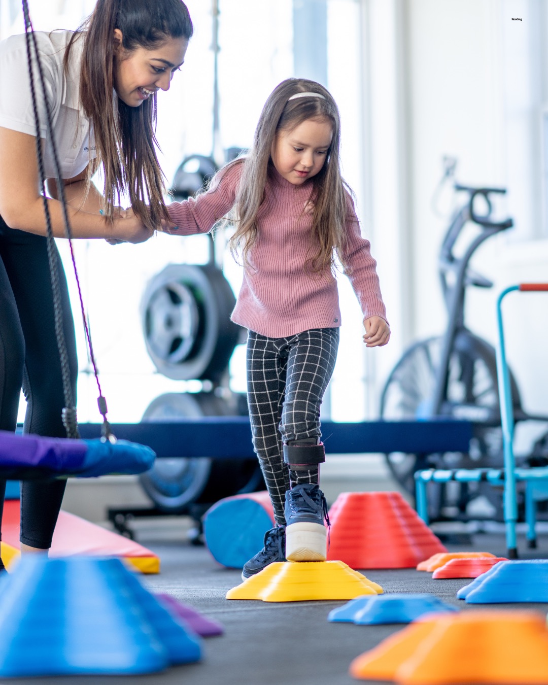 Pediatric physical therapist working with a toddler and therapy ball in the clinic